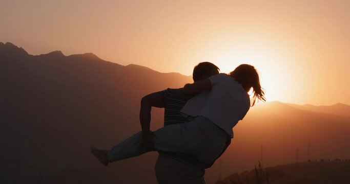 30s couple. Happy man spinning a woman on his back laughing enjoying honeymoon party together at sunset