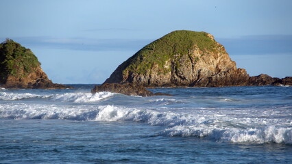 Waves breaking on the beach, in front of an island, in Zipolite, Mexico