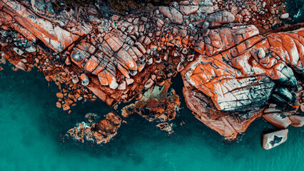 Drone Aerial of Orange Lichen Covered Boulders at Bay of Fires, Tasmania, Green Blue Water