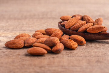 Salted almonds in wooden spoon on wooden background