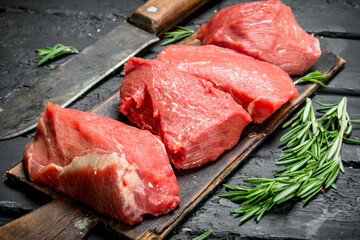 Raw meat. Pieces of beef with hatchet and rosemary branches.