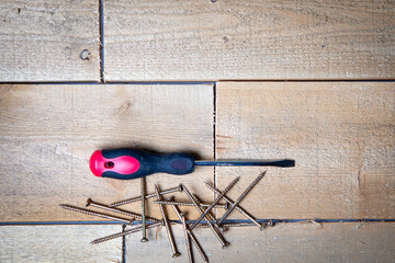 screw driver and screws on wooden background 