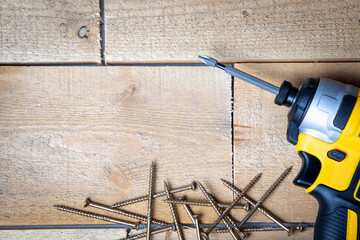 impact driver and screws on wood, construction equipment isolated on rustic wooden background