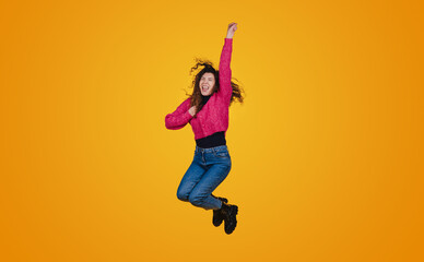 Fototapeta na wymiar Cheerful funny young woman in casual clothes jumping and spreading hands isolated on yellow wall background in studio. People sincere emotions, lifestyle