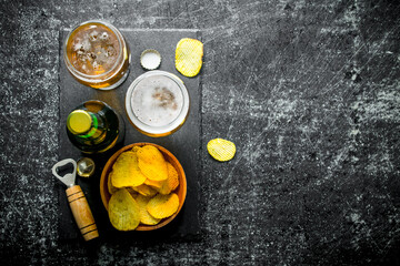 Beer with chips and opener on the cutting Board.