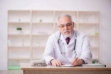 Old male doctor working in the clinic