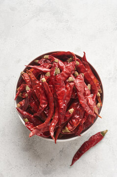 Dried Red Chili Or Cayenne Peppers In A White Bowl Or Container, Closeup Of Hot Spice Isolated On White Textured Surface With Copy Space, Taken From Above