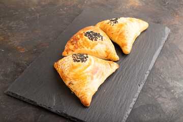 Homemade asian pastry samosa on black. side view.