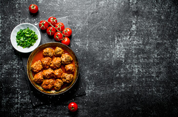 Meat balls in pan with tomatoes and chopped greens in bowl.