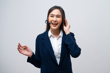 Beautiful Asian call center operator talking with customer using headset and microphone isolated on grey background.