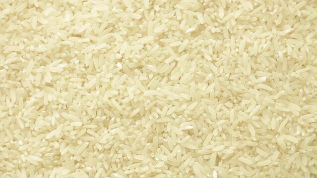 Macro top view of parboiled white grain rice seeds, organic natural refined carbohydrate. Flat lay rotation.
