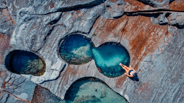Closeup Drone Aerial of Girl Sitting At Edge of Famous Figure 8 Pool In Royal National Park, Australia