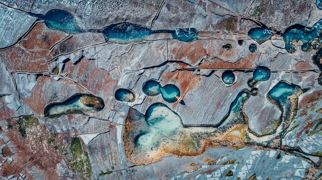 Drone Aerial of Girl Sitting At Edge of Famous Figure 8 Pool In Royal National Park, Australia