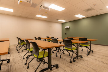 Interior of an office training, meeting, conference room with desks, chairs, and white board.  Nobody included in image.