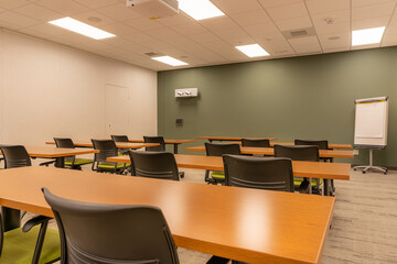 Interior of an office training, meeting, conference room with desks, chairs, and white board.  Nobody included in image.
