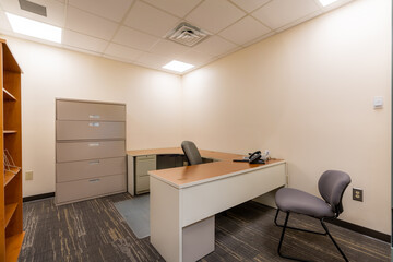 Depressing dull office with no window.  Typical uninspiring empty office with desk, chair, file...