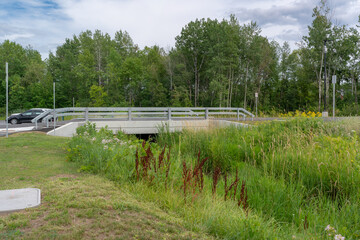 Three sided precast concrete bridge with guide rails installed over a wetland.  Precast bridge...