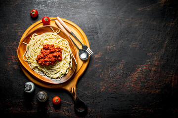 Pasta with Bolognese sauce in a wooden bowl with spices.