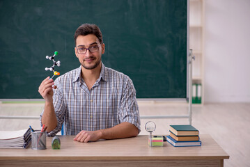 Young male teacher holding molecular model