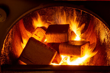 Wood briquettes (ruf type), made of beech and oak burning inside the wood fuel boiler. Alternative fuel, eco fuel, bio fuel.
