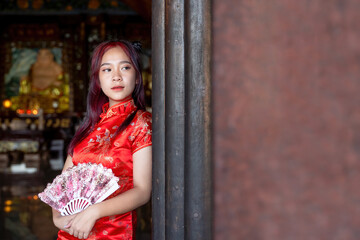 portrait of beautiful asian woman in traditional Chinese dress holding fan in Chinese shrine in Chinese new year festival celebration
