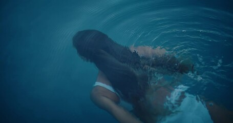 Beautiful young woman swimming underwater in luxury pool on vacation at tropical resort spa