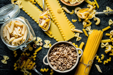 Pasta background. Different types of dry pasta in the pot and bowl.