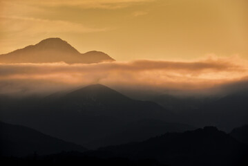 美しい夕日が差す山間と流れる雲海