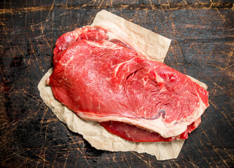 Raw steak of juicy beef on paper.