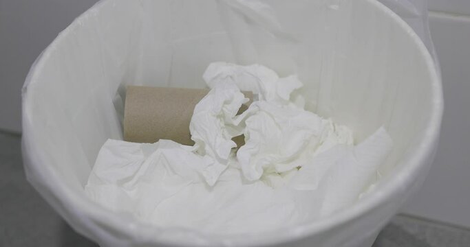 Close-up throw used tissues into the trash can in clean and modern bathroom. 4k video footage.