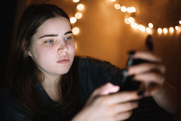 Teenage girl using smart phone at home at night