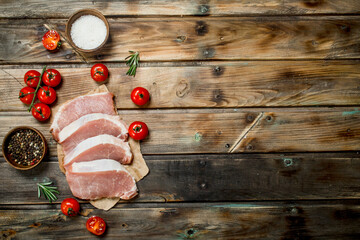 Raw pork steaks with tomatoes and rosemary.