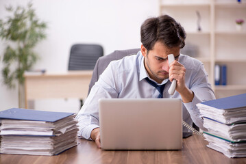 Young male employee and too much work in the office