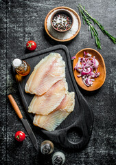 Tilapia fish fillet with spices and onion slices in bowls.