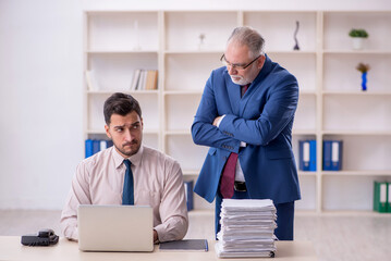 Old male boss and young male employee in bullying concept