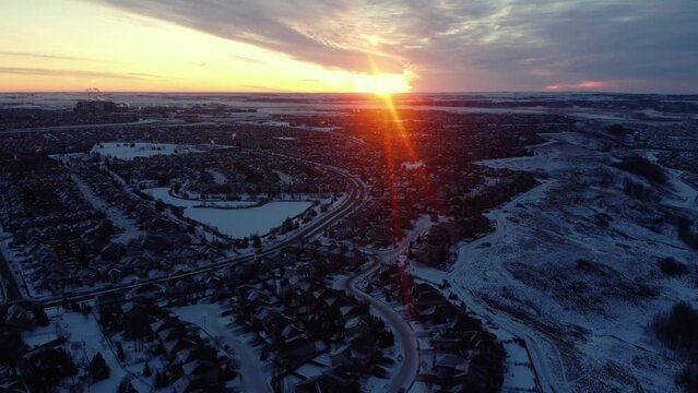 Flying drone in Calgary during a beautiful winter sunrise with god rays over community