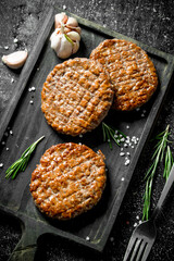 Cutlets on a cutting Board with garlic and a fork.