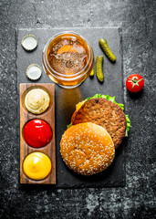 Burger with beer, sauces and gherkins.