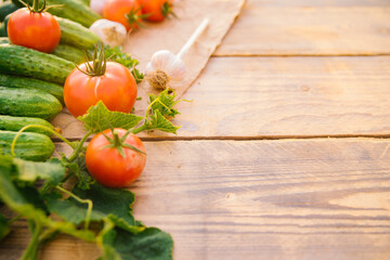 Fresh vegetables on a wooden background. Empty space for the text. Cucumbers, tomatoes, garlic, dill. Top view.