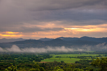 Fototapeta premium A bird's-eye view of field countryside Surrounded by mountains and nature in the rainy or farming season at Wat Phra That Doi Phra Chan of Lampang Province, Thailand.