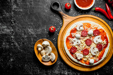 Preparation pizza. Rolled out dough with tomato paste, sausages, mushrooms and cheese.