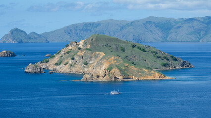 Remote, wild and uninhabited tropical island with a tourism liveaboard tour boat in Komodo National Park near Flores Island, Indonesia