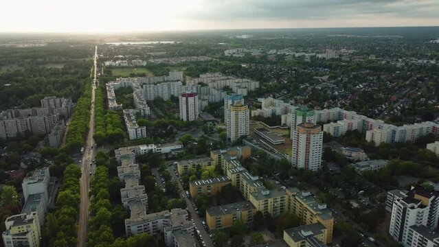 Amazing cinematic aerial shot of huge buildings and lush green areas in a ghetto during a sunset on the semi cloudy sky