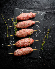 Raw kebab of ground beef with thyme and pieces of salt.