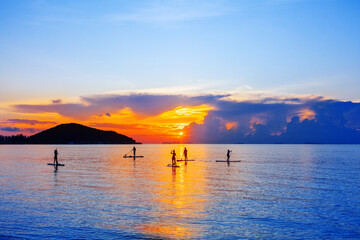 People silhouettes stand SUP paddle boarding, sea sunset beach, active young man woman surfing...