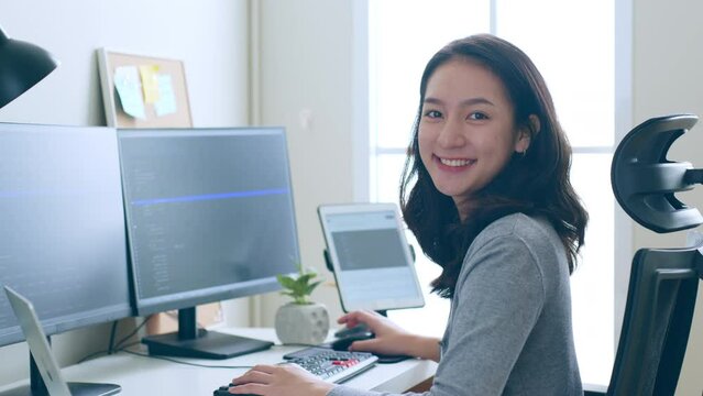 Portrait young Asian woman developer programmer, software engineer, IT support, look at camera and smile enjoy working at office.