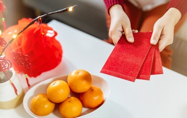 Asian Woman giving red envelope for Lunar New Year celebrations. Hand hold red packet