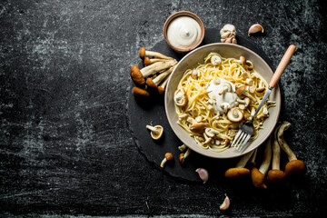 The pasta with the sauce in a bowl and fresh mushrooms.