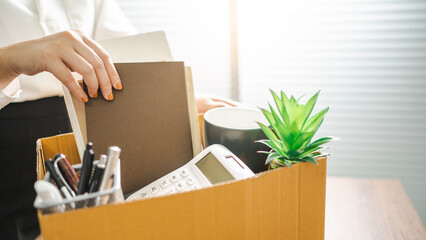 Business woman sending resignation letter and packing Stuff Resign Depress or carrying business cardboard box by desk in office. Change of job or fired from company - obrazy, fototapety, plakaty