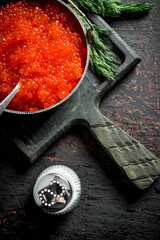 Red caviar in bowl with spoon, dill and salt.